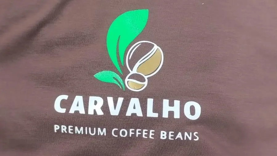 Camiseta marrom dobrada com o logotipo Carvalho Premium Coffee Beans estampado no peito.