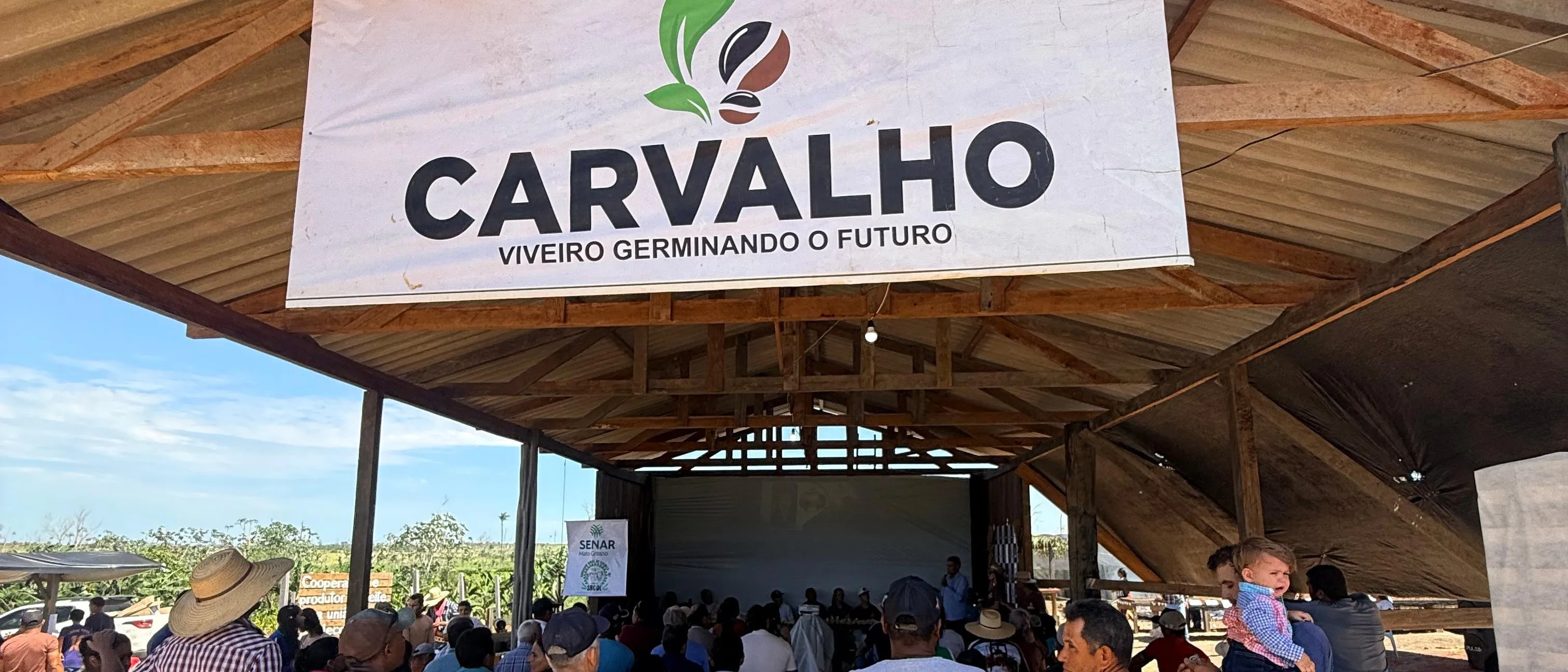 A Carvalho banner hanging on a timber shed under construction at the nursery, with members gathered underneath.